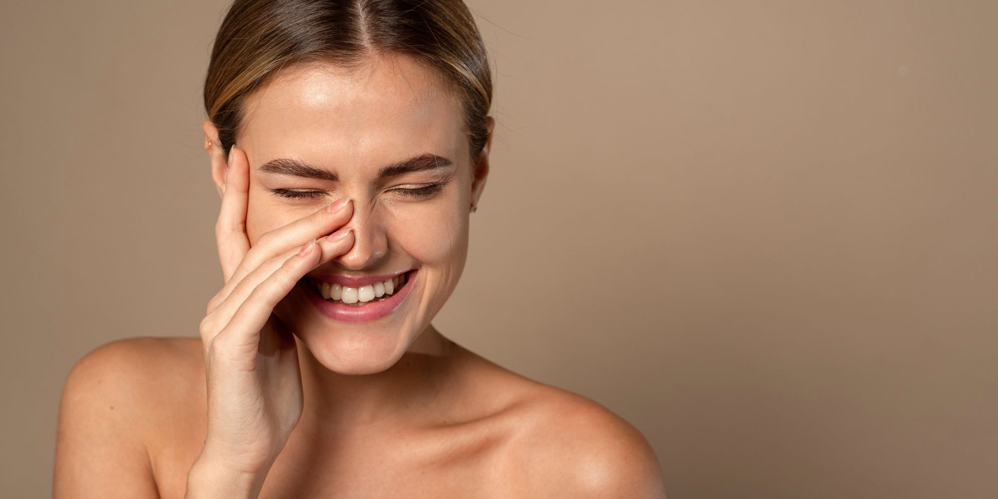 Lachende Frau mit sensibler Haut auf warmem Hintergrund