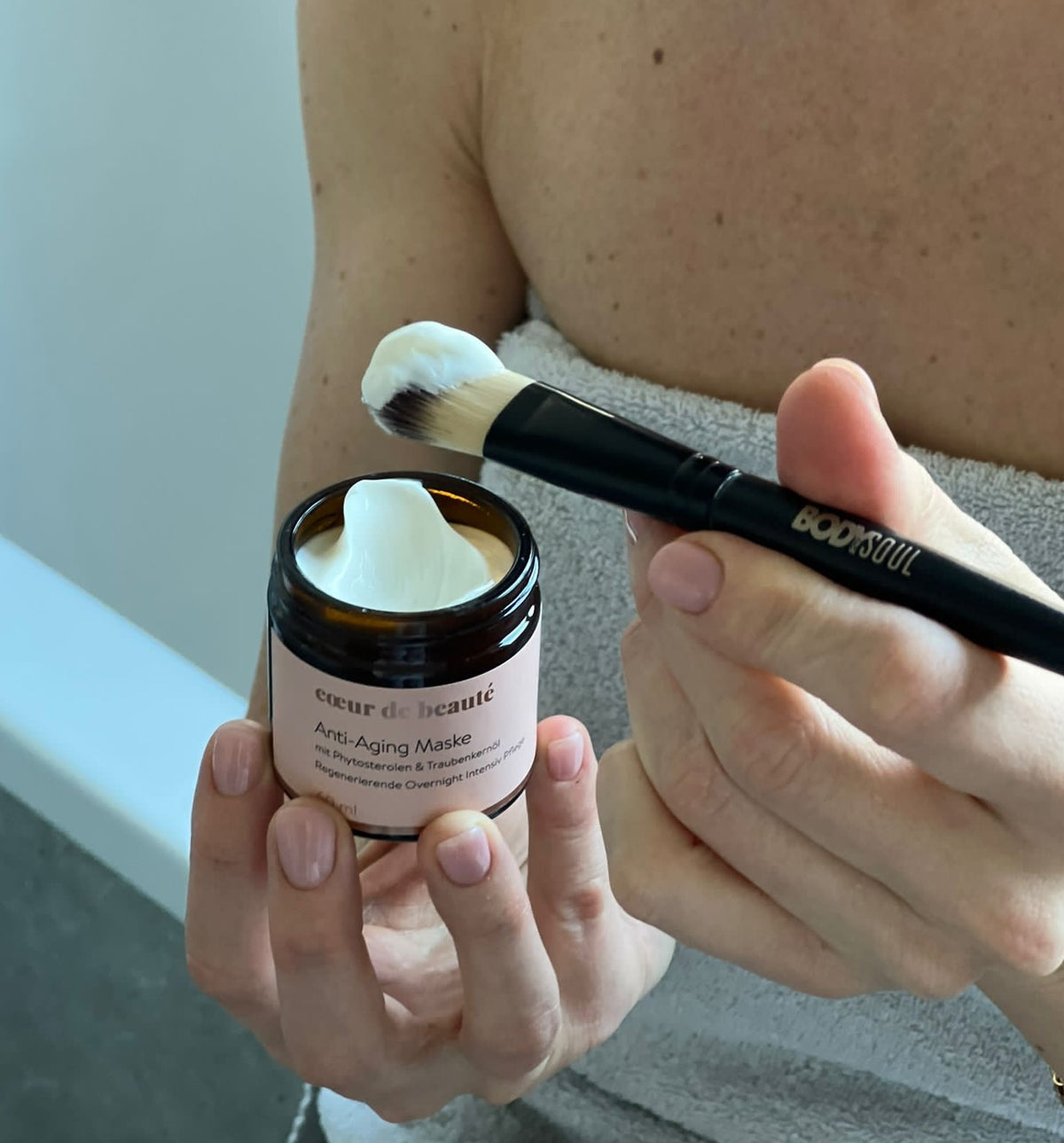 Hand einer Frau hält die Anti-Aging Overnight Maske von cœur de beauté.