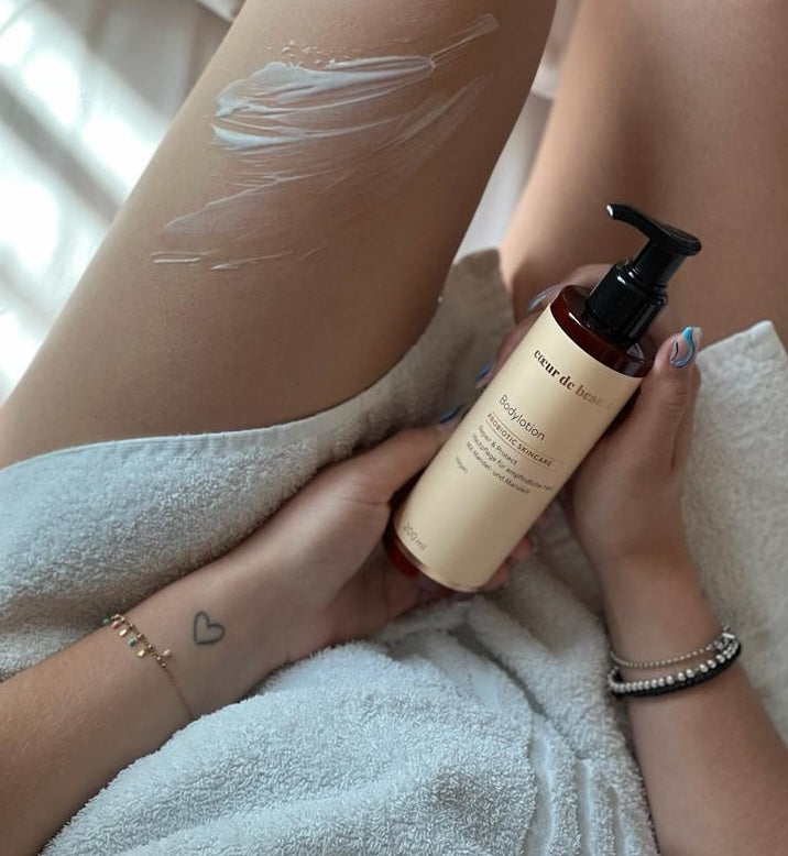 Frau hält die probiotische Bodylotion von cœur de beauté in der Hand.