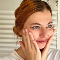 Frau sprüht ein Gesichtsspray auf die Haut.