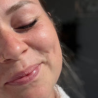 Frau lächelt und hält ihr Gesicht in die Sonne.