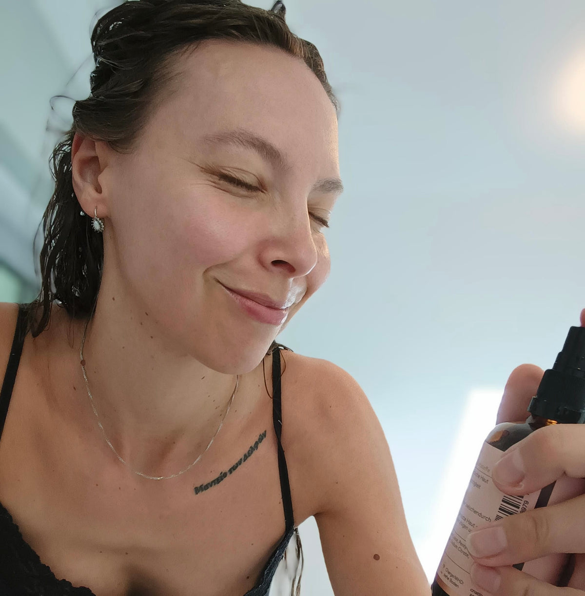 Frau sprüht das Aloe Moisture Spray von cœur de beauté auf das Gesicht.