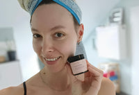 Frau hält einen Gesichtspflege-Tiegel von cœur de beauté nahe ihres Gesichts.