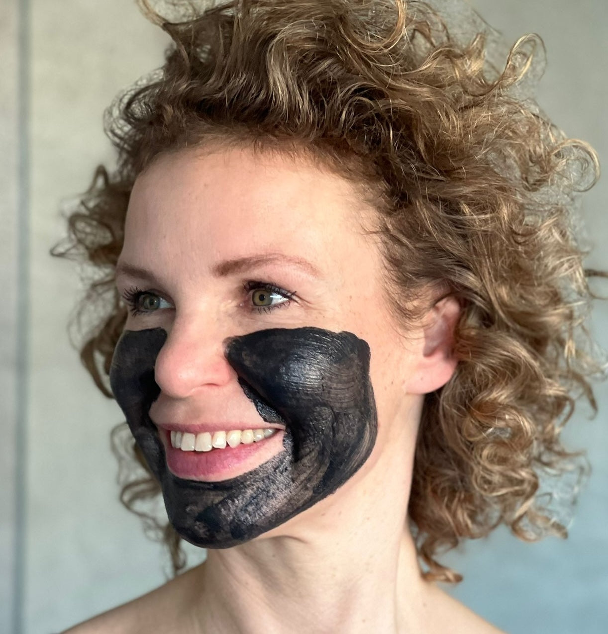 Frau mit aufgetragener schwarzer Peeling-Maske im Gesicht.