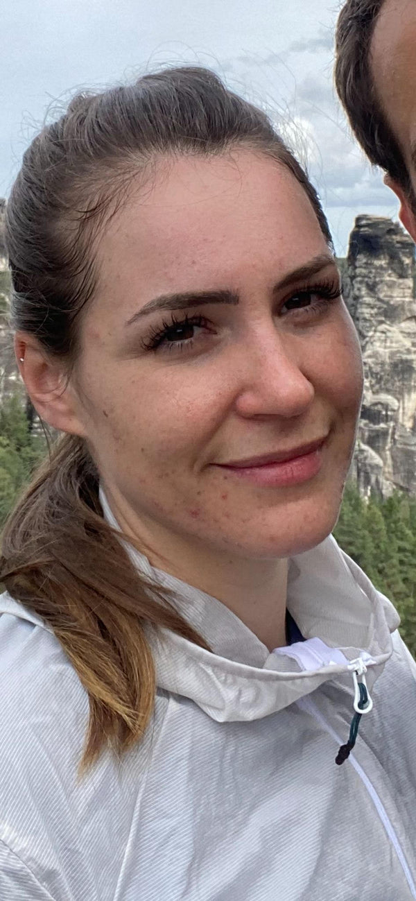 Lächelnde Kundin mit natürlicher, sensibler Gesichtshaut schaut in die Kamera.